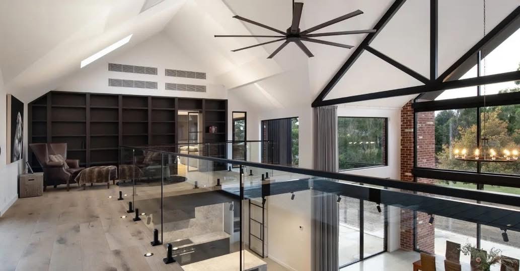 Glass mezzanine balustrade with black handrails in a bright vaulted room