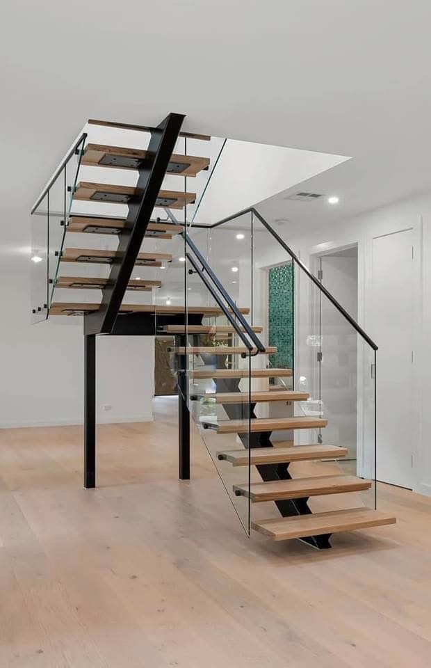 Glass stair balustrade with black handrails and open timber treads