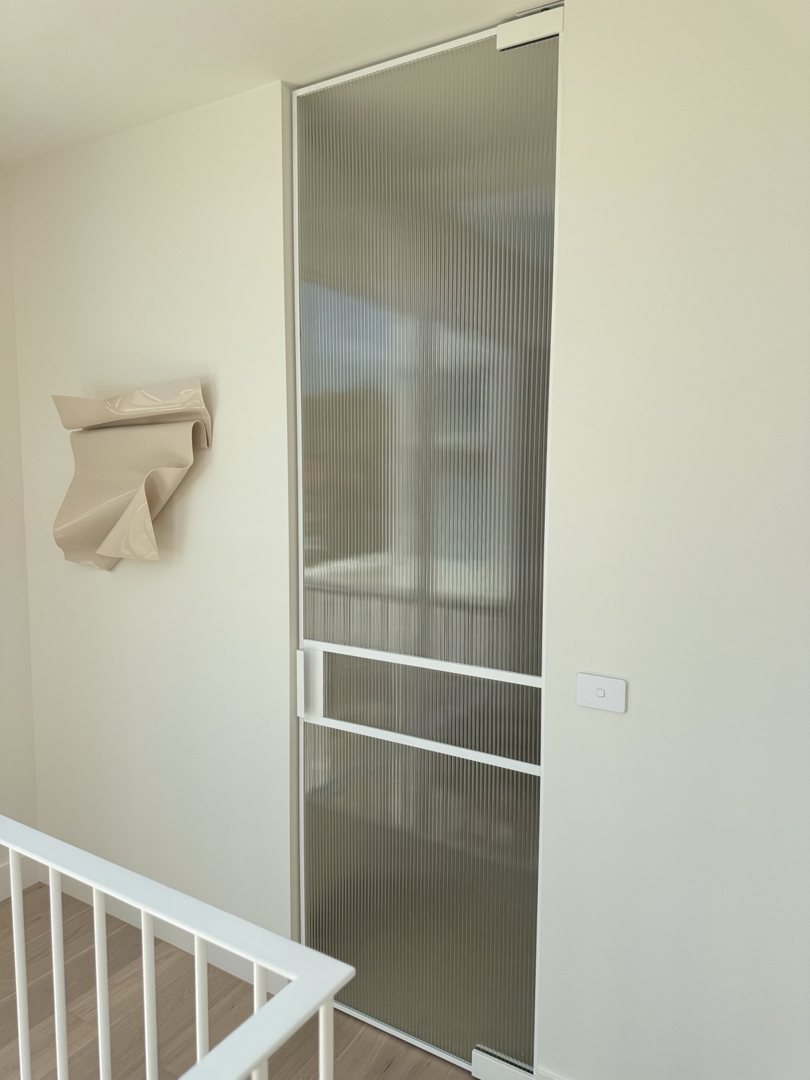 Tall white-framed internal door with fluted glass beside a staircase