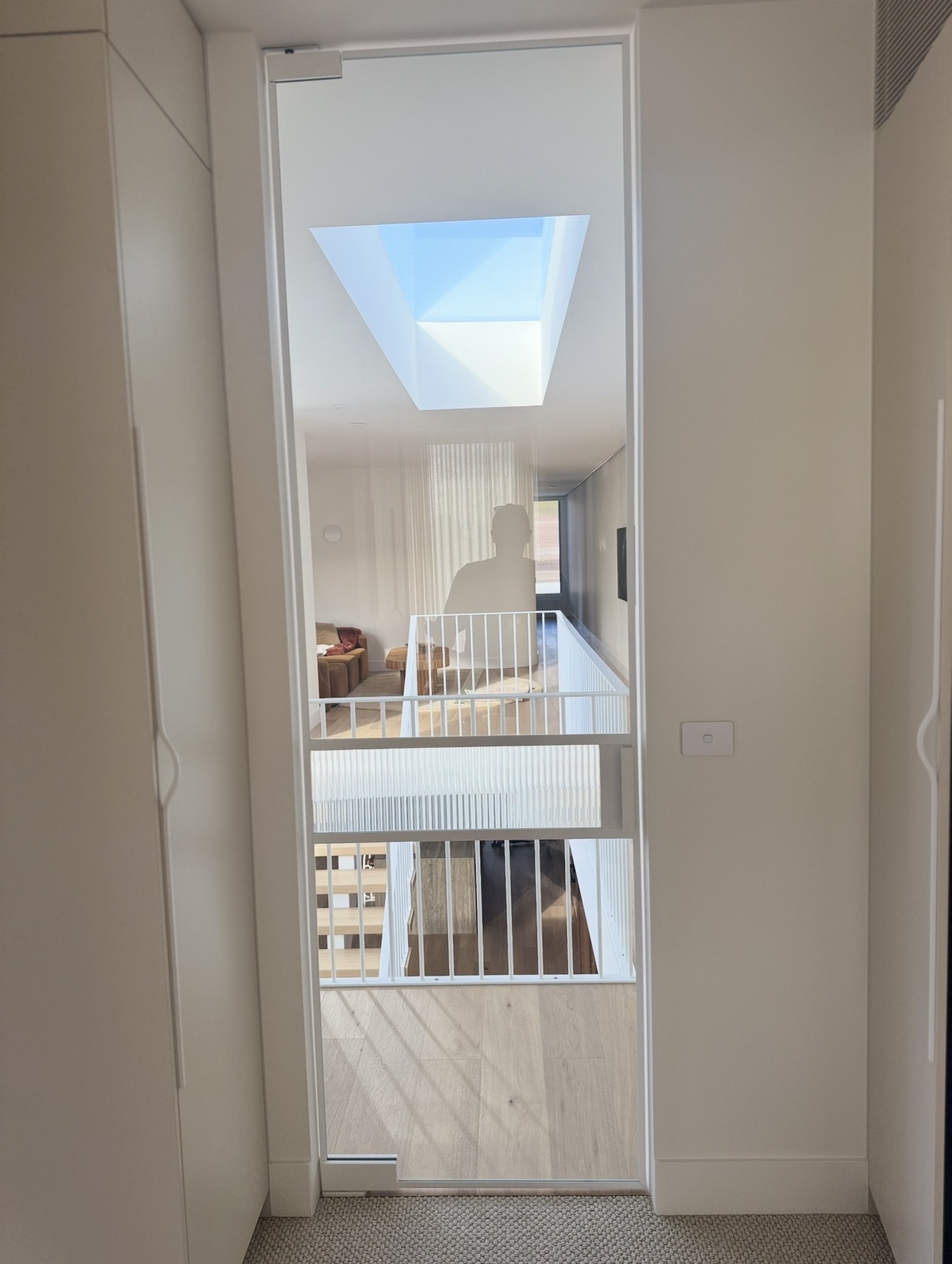 Tall white-framed clear glass door with a fluted band overlooking a stair landing
