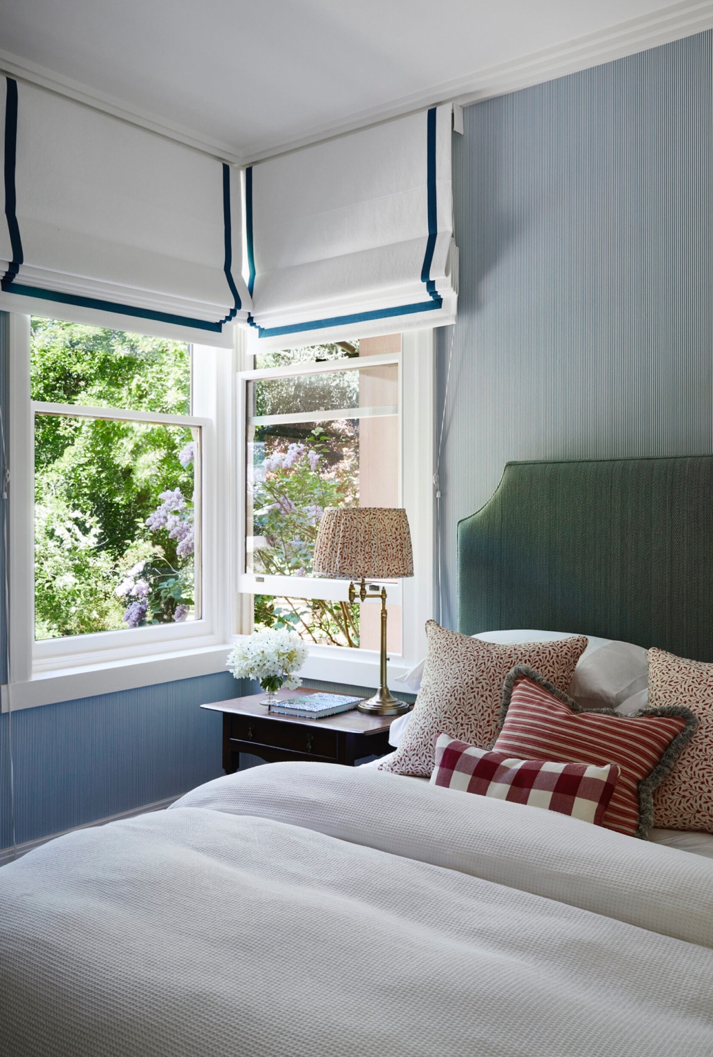 White timber bedroom windows with Roman blinds and a garden view