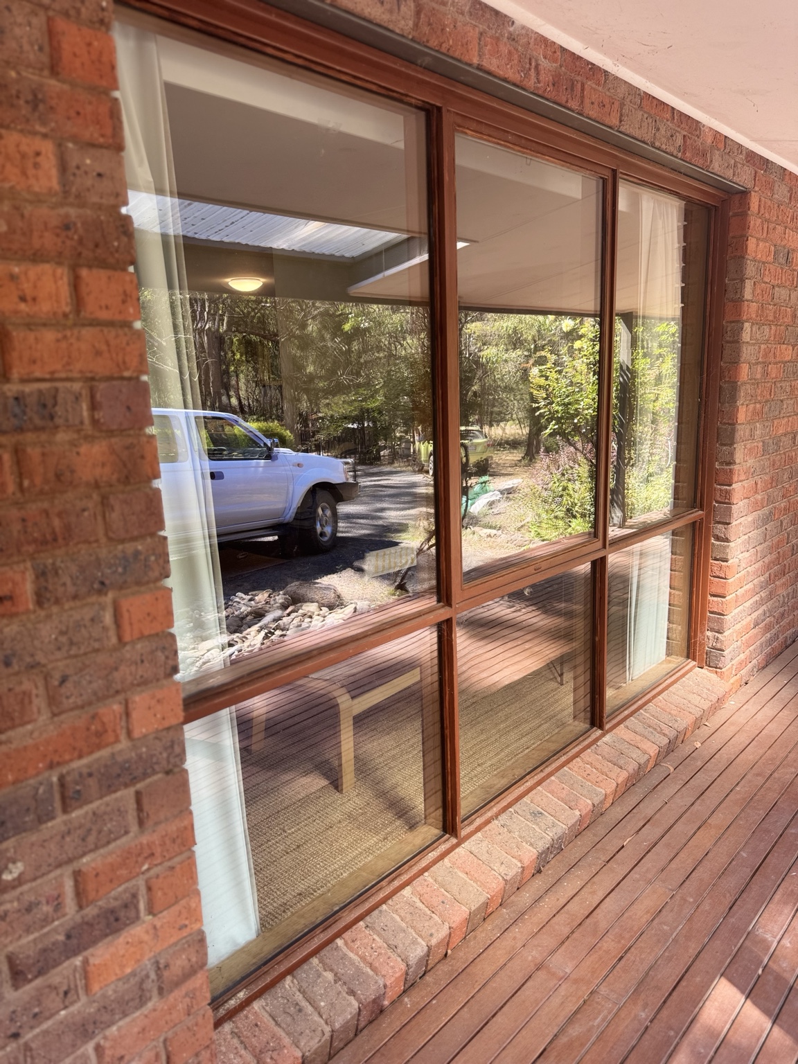 Timber windows set in red brick beside a timber deck