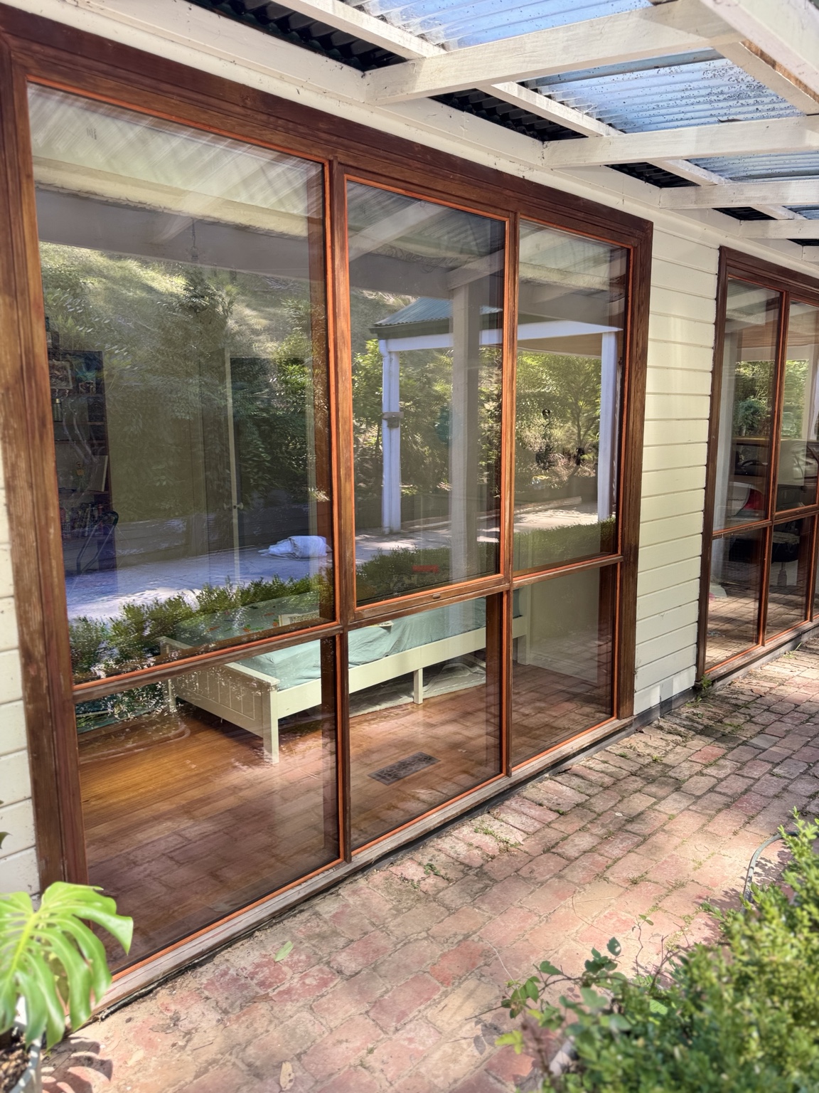 Timber-framed windows along a weatherboard home with a covered brick veranda