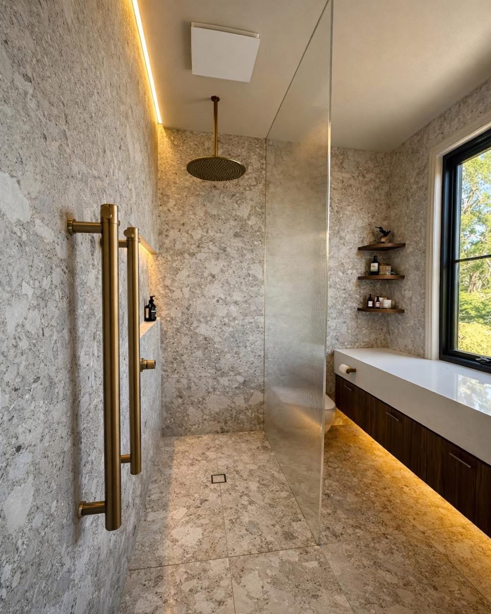 Tall fixed shower glass panel in a stone bathroom with warm lighting